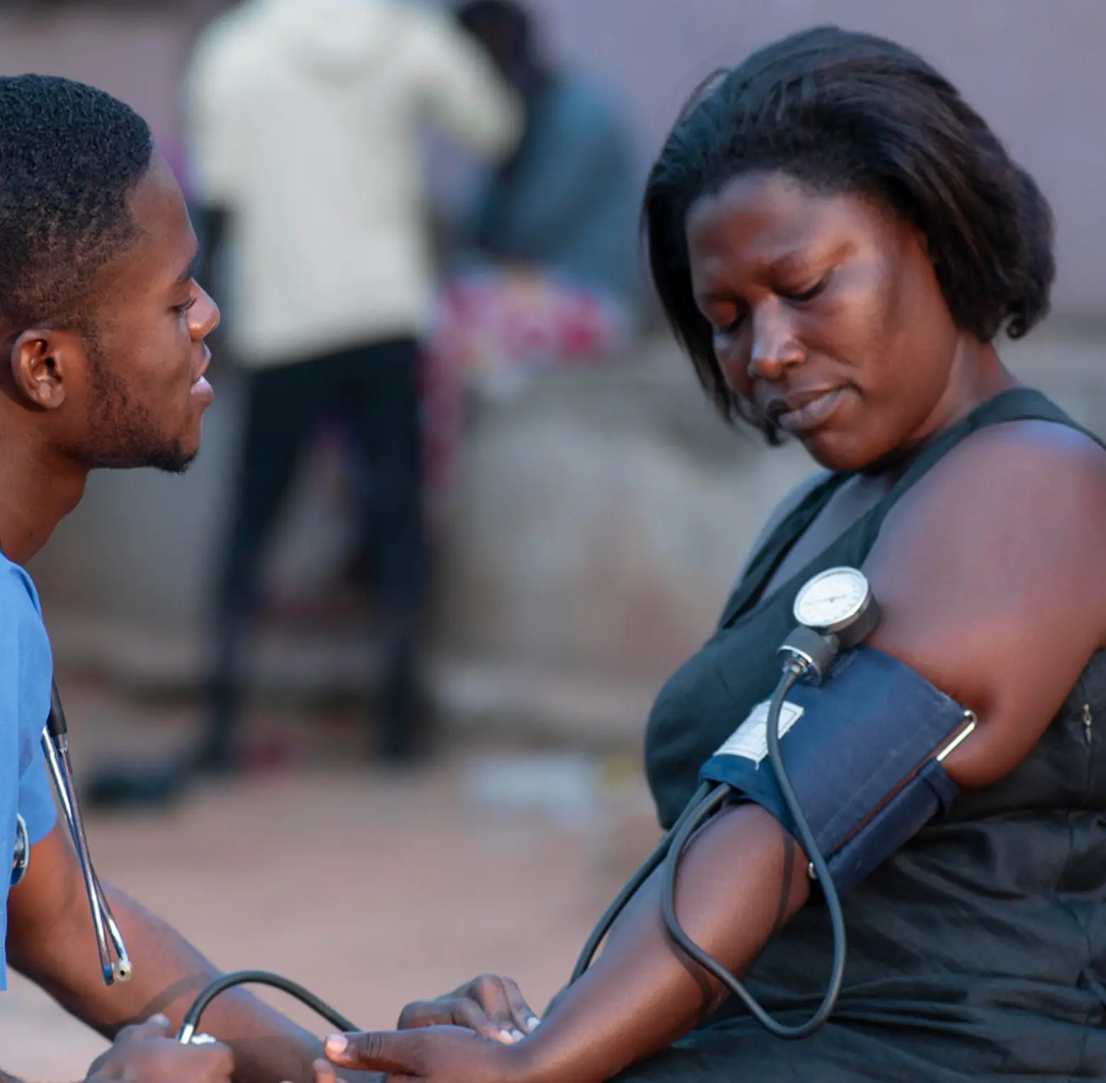 Health worker checking an older woman's blood pressure
